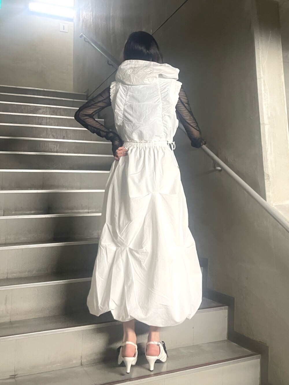 ホワイト系のベスト、ホワイト系のスカート、ブラック系のTシャツ/カットソーを着用したレディースの冬コーディネートの3枚目の写真