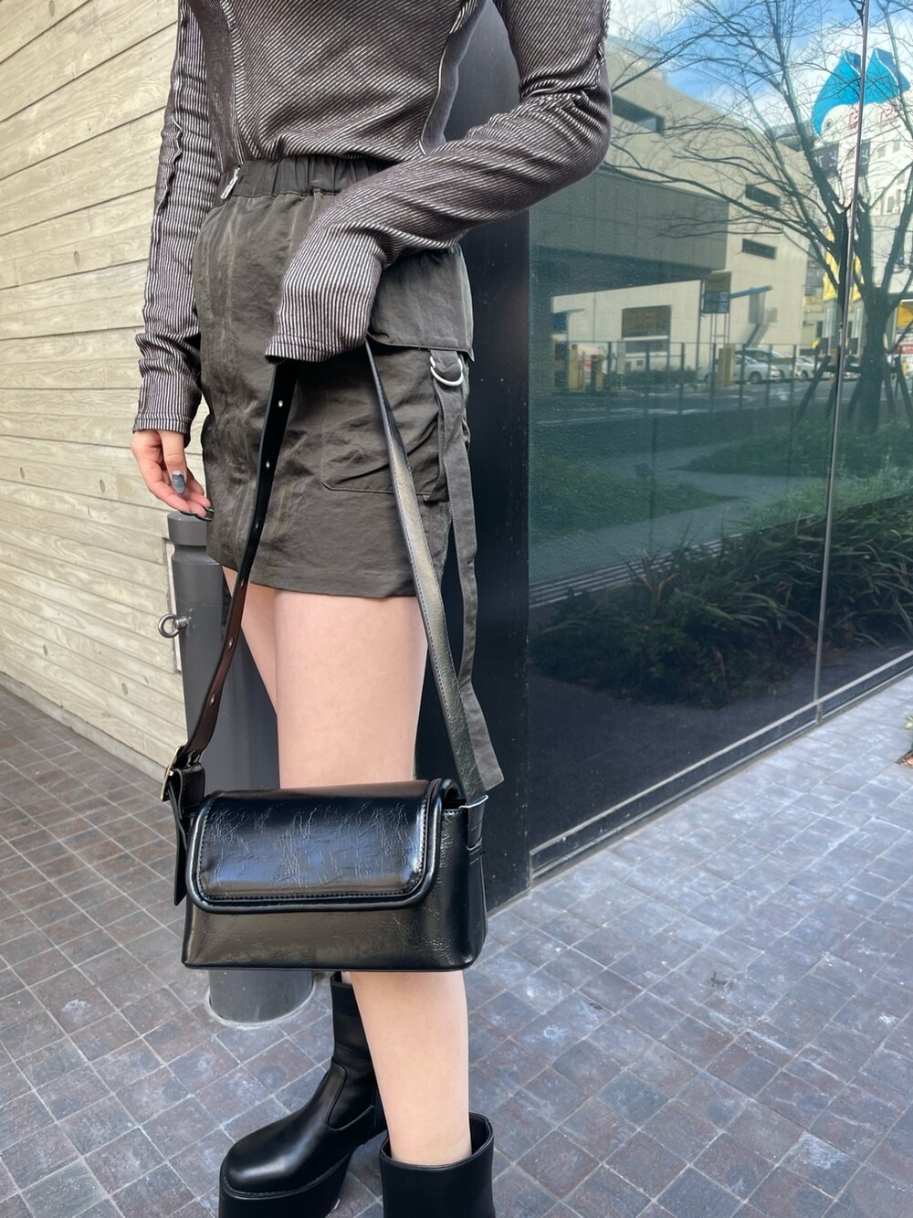 ブラック系のショルダーバッグ、グレー系のTシャツ/カットソー、ベージュ系のスカートを着用したレディースの冬コーディネートの7枚目の写真