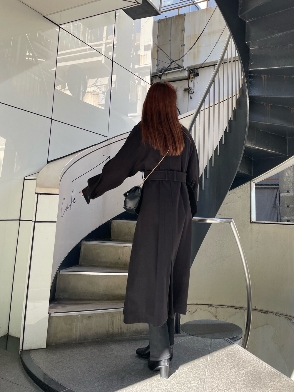 ブラック系のステンカラーコート、ホワイト系のニット/セーター、ブラック系のデニムパンツを着用したレディースの秋コーディネートの4枚目の写真