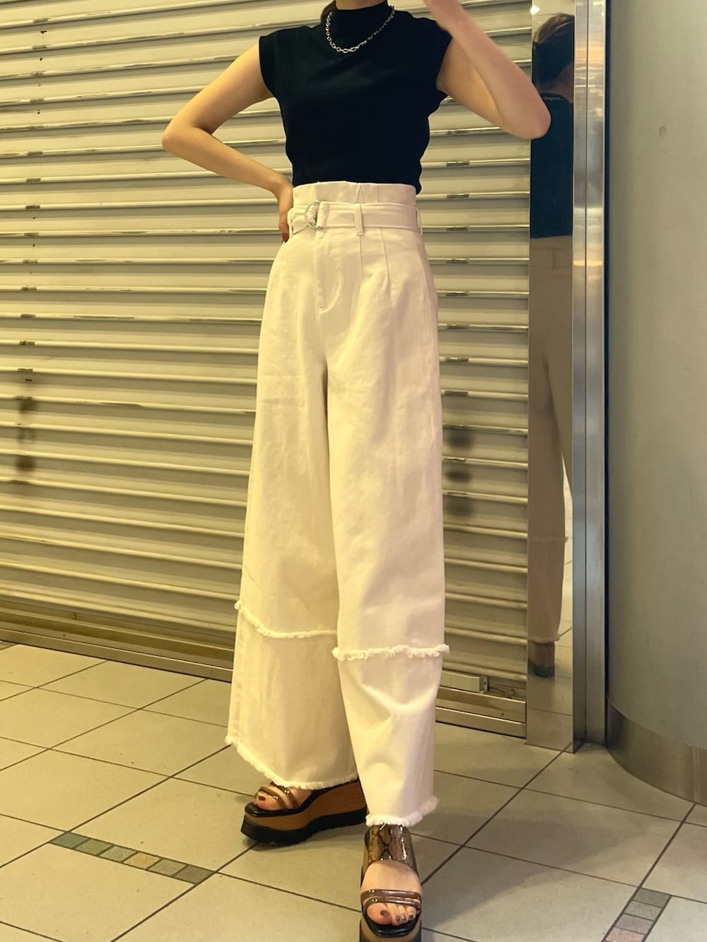 ブラック系のニット/セーター、ホワイト系のデニムパンツ、ブラック系のサンダルを着用したレディースの春コーディネートの4枚目の写真