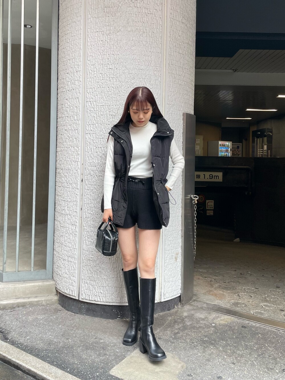 ブラック系のダウンベスト、ホワイト系のニット/セーター、ブラック系のその他パンツを着用したレディースの秋コーディネートの2枚目の写真