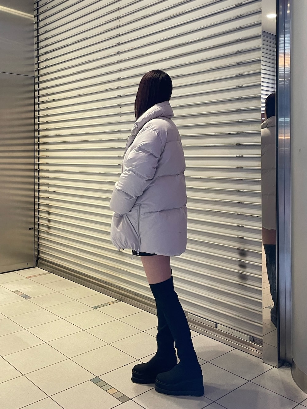 ブラック系のブーツ、ブラック系のニット/セーター、グレー系のダウンジャケット/コートを着用したレディースの冬コーディネートの3枚目の写真