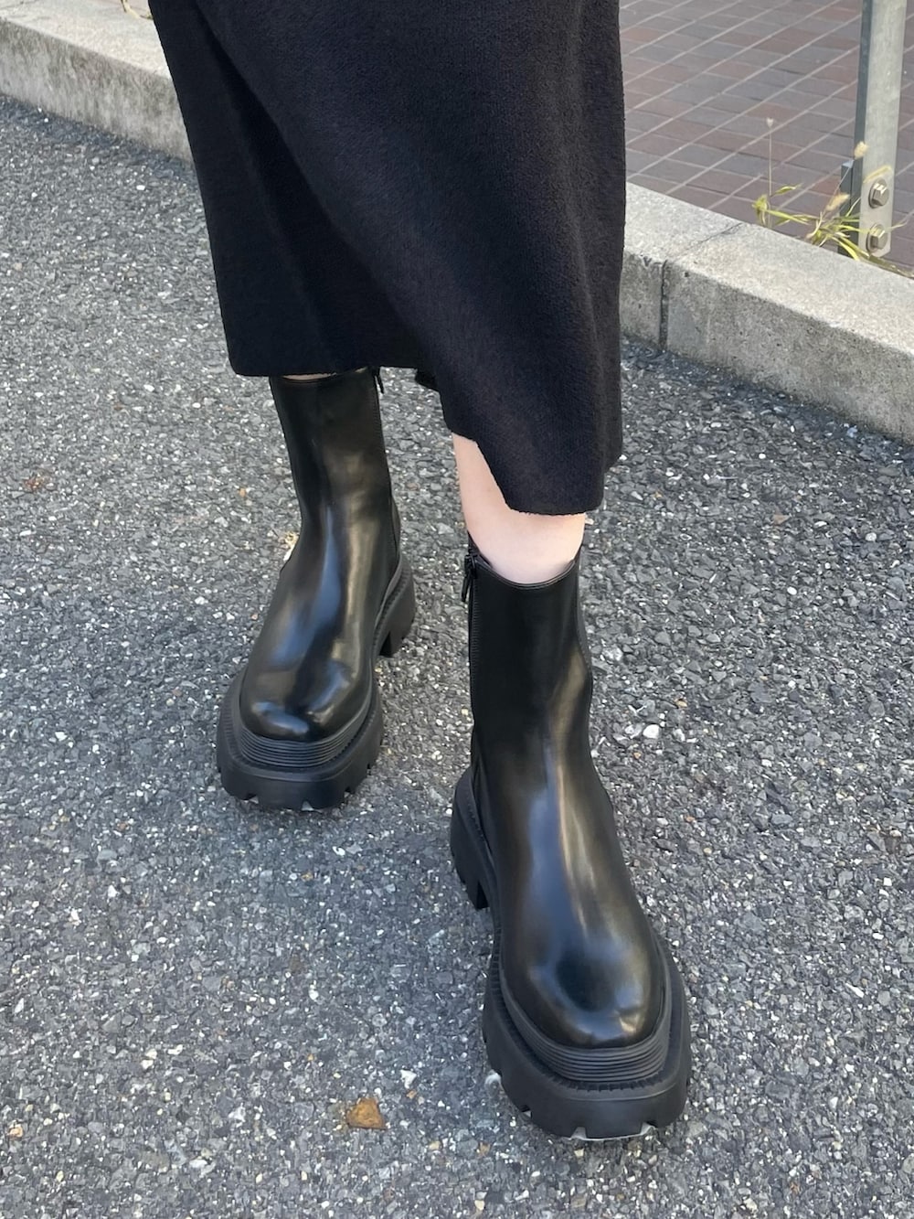 ブラック系のニット/セーター、ブラック系のスカート、ブラック系のブーツを着用したレディースの冬コーディネートの9枚目の写真