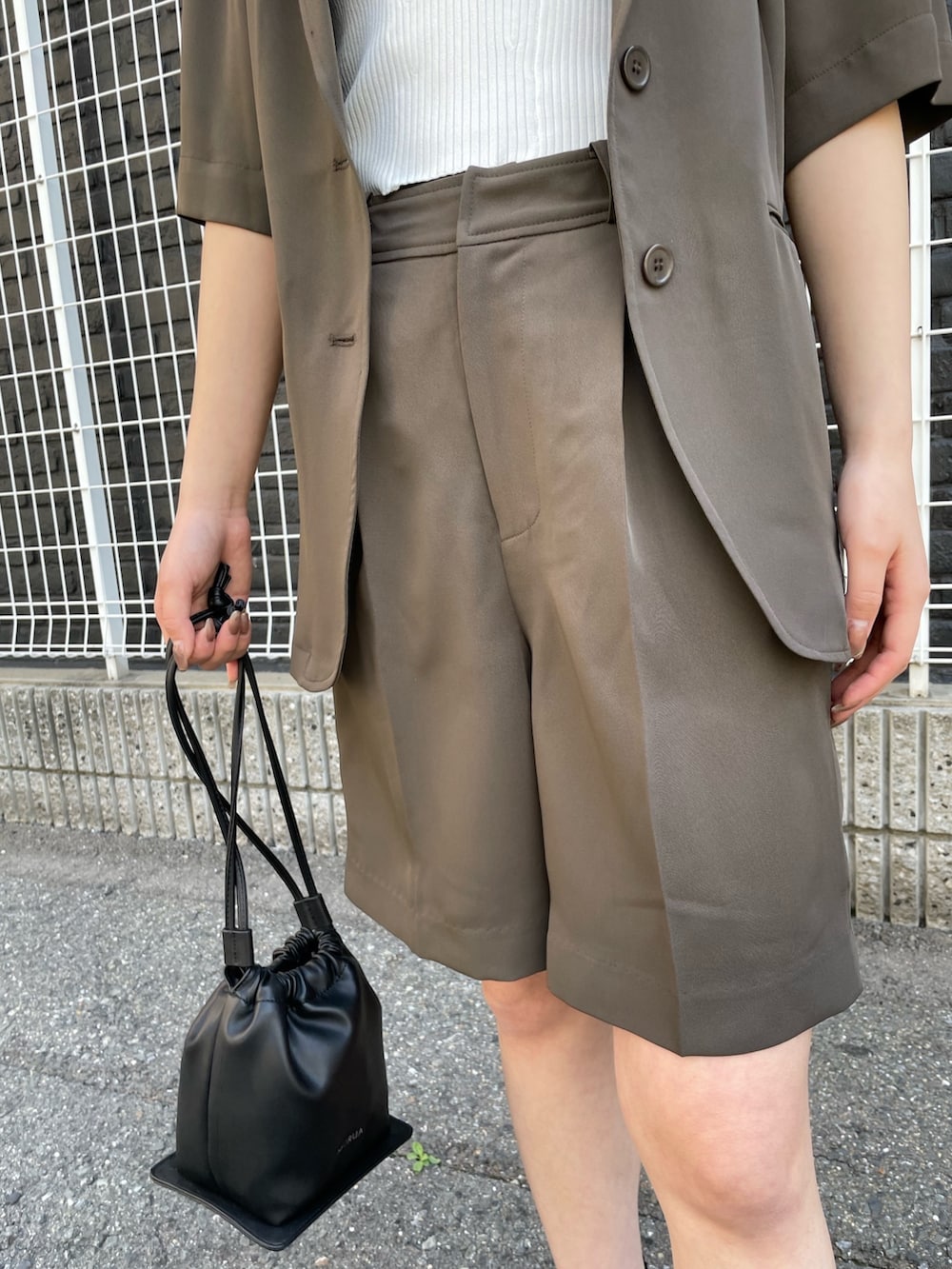 ブラウン系のテーラードジャケット、ホワイト系のタンクトップ、ブラウン系のスラックスを着用したレディースの春コーディネートの6枚目の写真