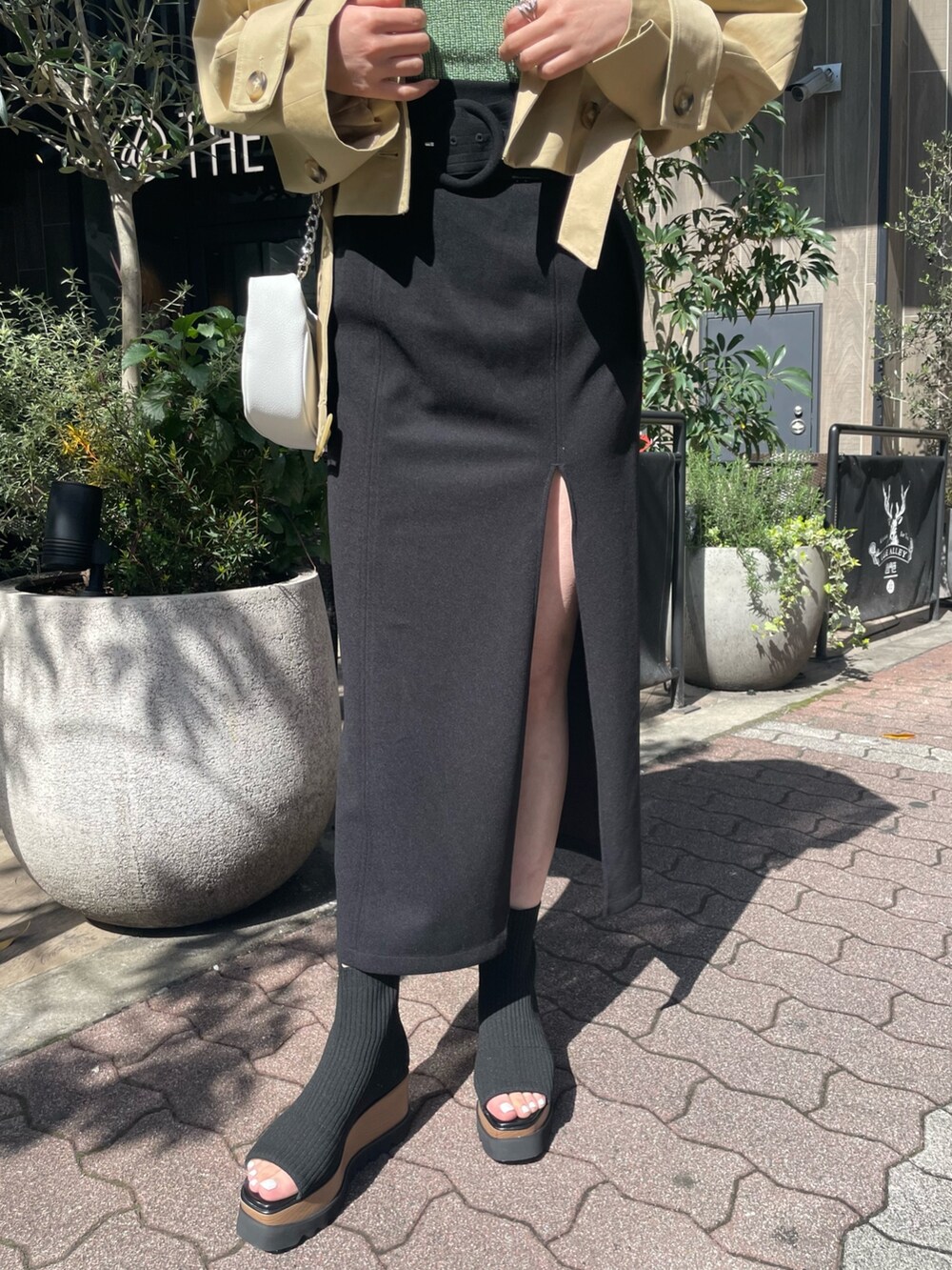 ホワイト系のハンドバッグ、ブラック系のブーツ、ブラック系のスカートを着用したレディースの春コーディネートの7枚目の写真