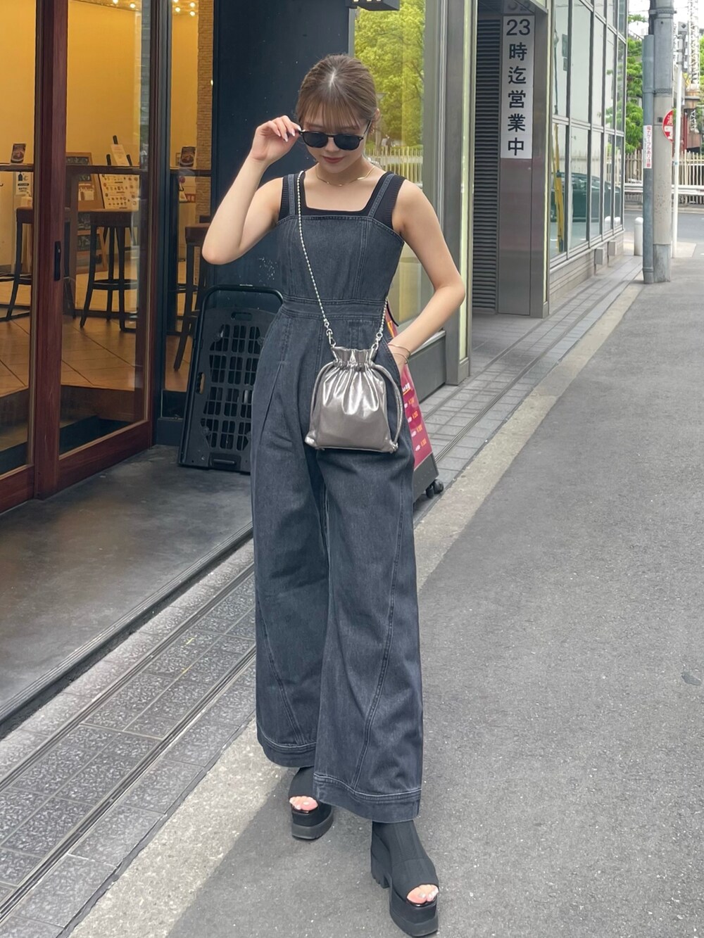 グレー系のショルダーバッグ、ブラック系のブーツ、ブラック系のニット/セーターを着用したレディースの春コーディネートの2枚目の写真