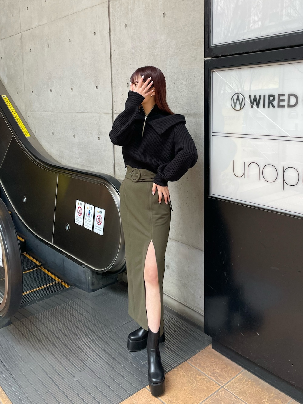 ブラック系のブーツ、グリーン系のスカート、ブラック系のニット/セーターを着用したレディースの冬コーディネートの2枚目の写真