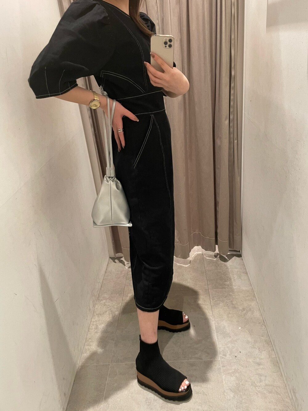 ブラック系のブーツ、ブラック系のワンピース、シルバー系のハンドバッグを着用したレディースの春コーディネートの2枚目の写真