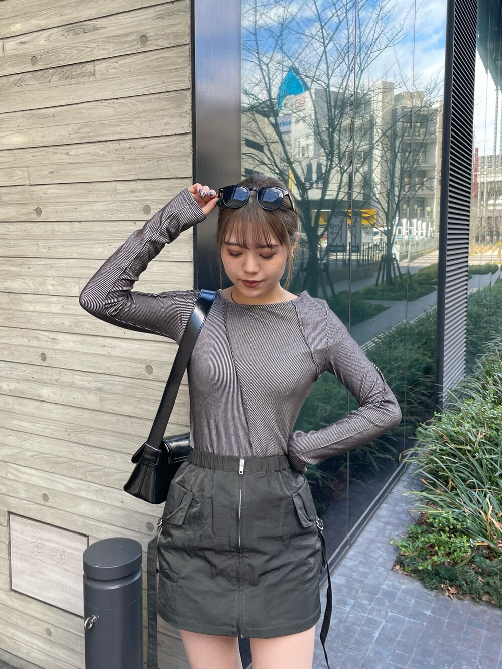 ブラック系のショルダーバッグ、グレー系のTシャツ/カットソー、ベージュ系のスカートを着用したレディースの冬コーディネートの5枚目の写真