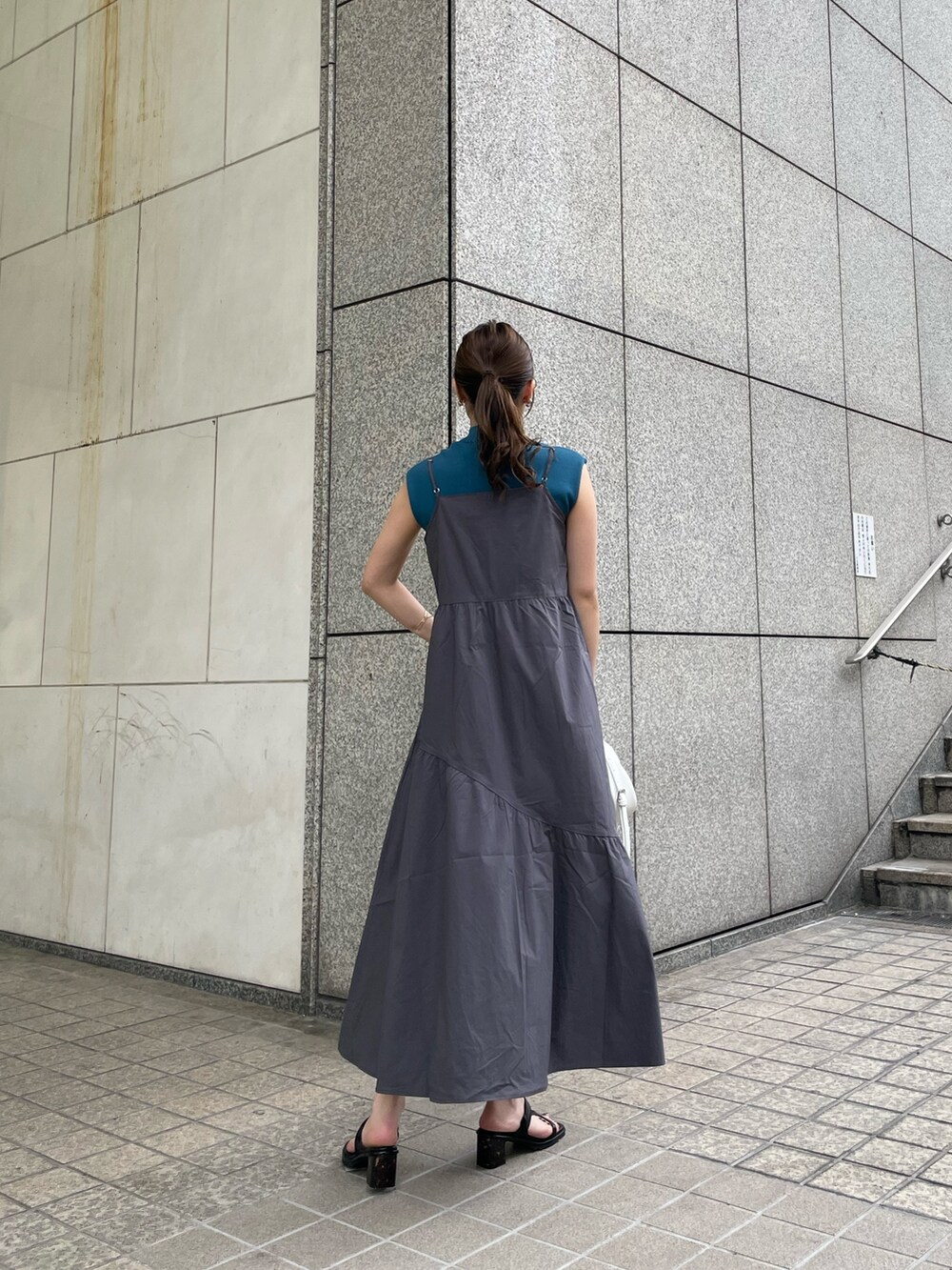 グレー系のワンピース、ブルー系のニット/セーター、ホワイト系のハンドバッグを着用したレディースの春コーディネートの3枚目の写真