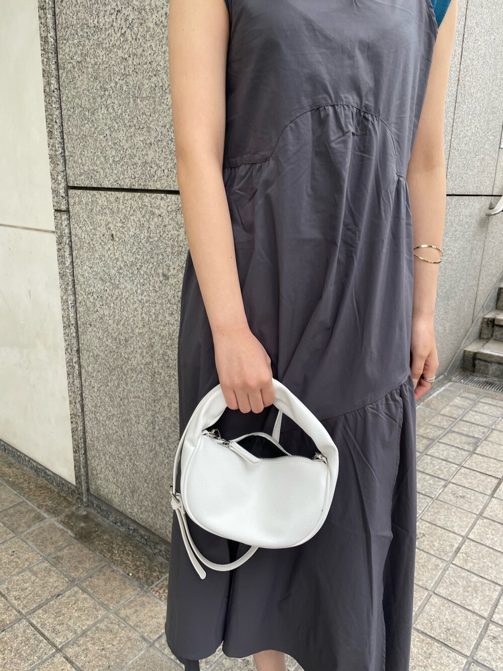 グレー系のワンピース、ブルー系のニット/セーター、ホワイト系のハンドバッグを着用したレディースの春コーディネートの7枚目の写真