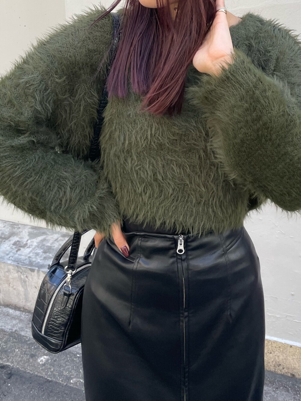 グリーン系のニット/セーター、ブラック系のボストンバッグ、ブラック系のスカートを着用したレディースの秋コーディネートの5枚目の写真