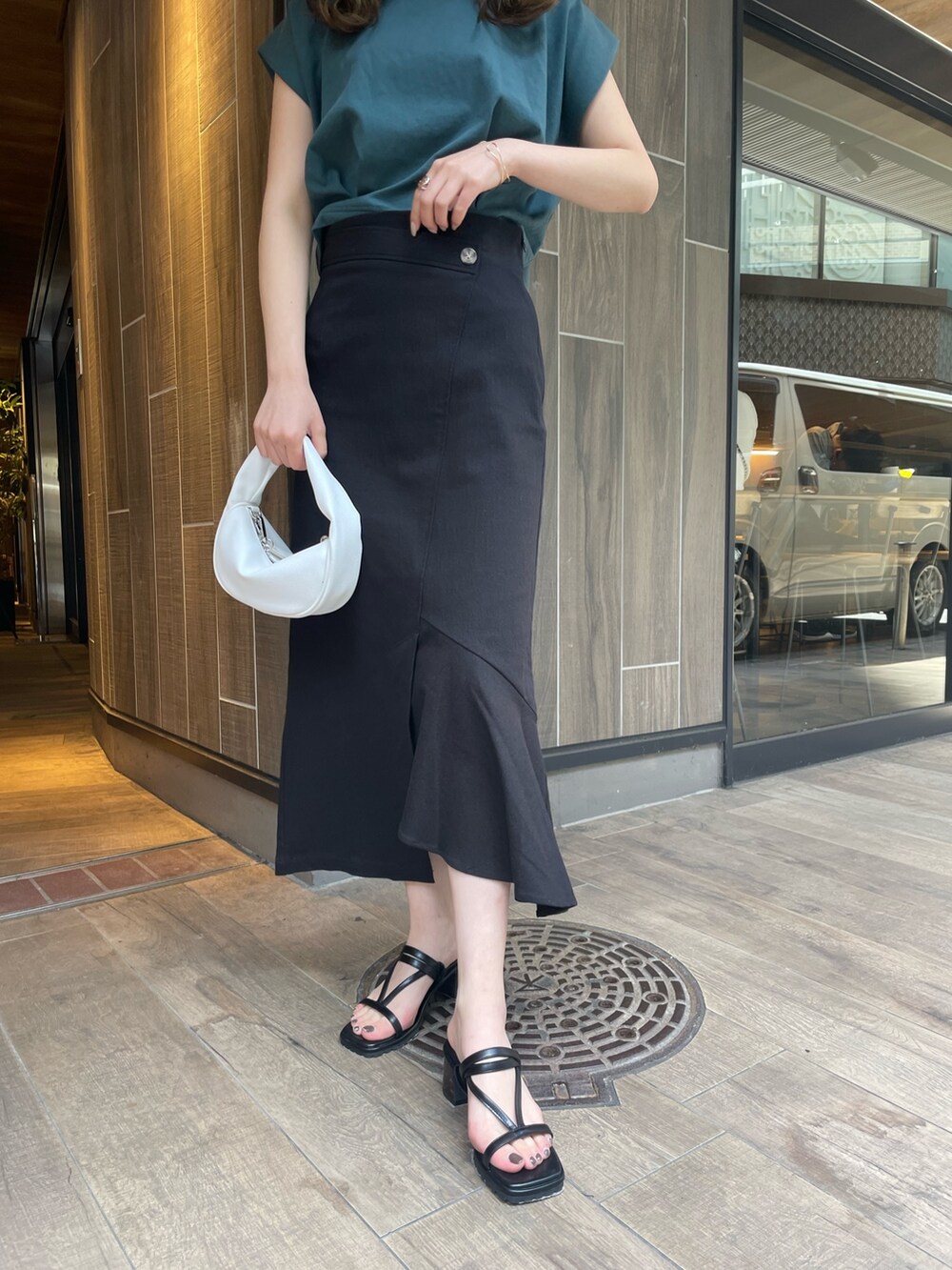 グリーン系のTシャツ/カットソー、ブラック系のスカート、ホワイト系のハンドバッグを着用したレディースの春コーディネートの5枚目の写真