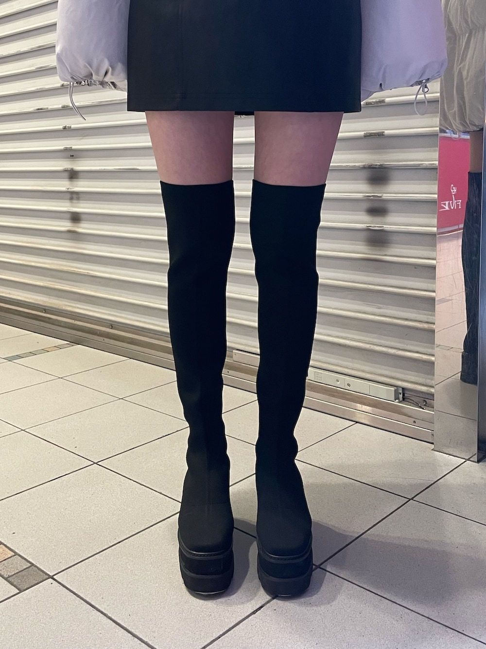 ブラック系のブーツ、ブラック系のニット/セーター、グレー系のダウンジャケット/コートを着用したレディースの冬コーディネートの8枚目の写真