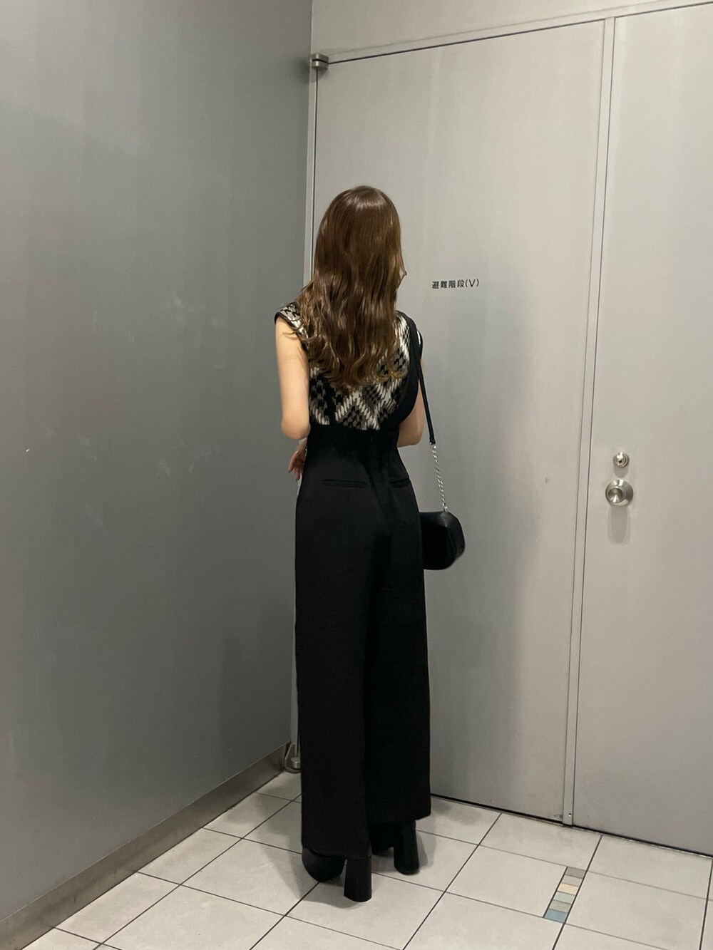 ブラウン系のニット/セーター、ブラック系のスラックス、ブラック系のハンドバッグを着用したレディースの夏コーディネートの4枚目の写真