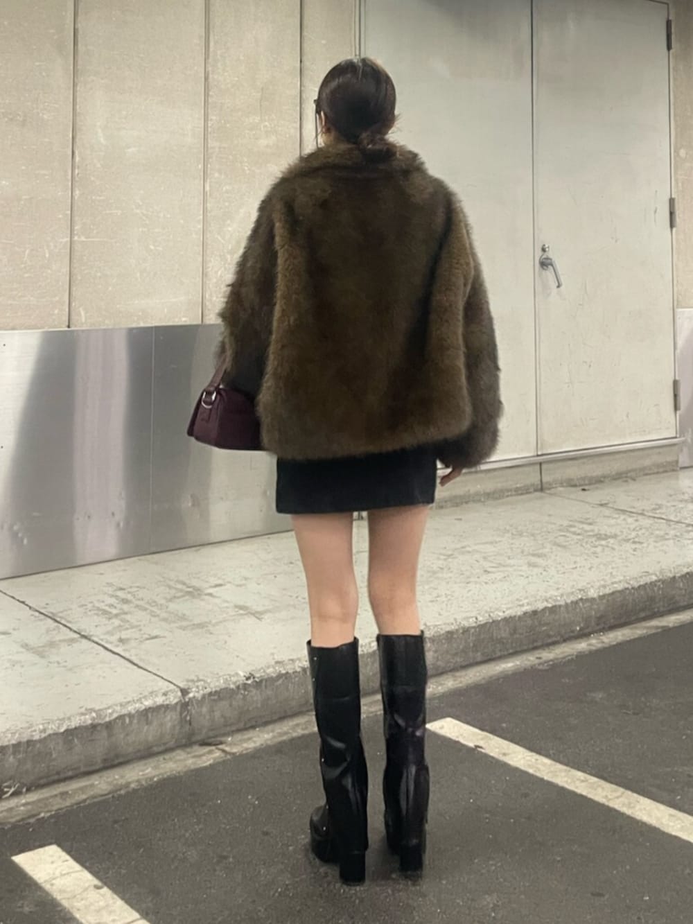 ブラウン系のブルゾン、ブラック系のスカート、ブラック系のブーツを着用したレディースの秋コーディネートの3枚目の写真