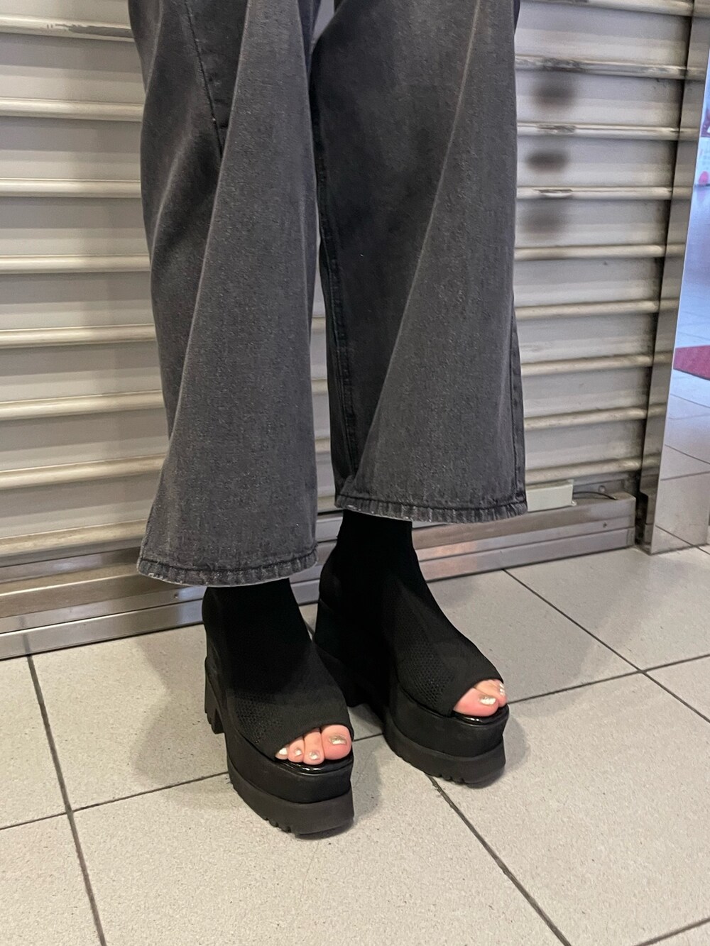 ホワイト系のニット/セーター、ブラック系のデニムパンツ、ブラック系のブーツを着用したレディースの春コーディネートの7枚目の写真