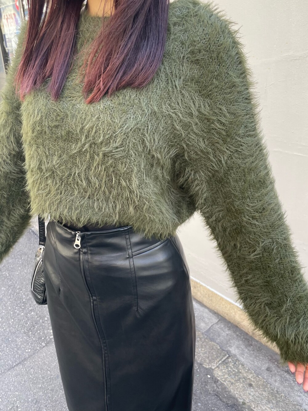 グリーン系のニット/セーター、ブラック系のボストンバッグ、ブラック系のスカートを着用したレディースの秋コーディネートの6枚目の写真