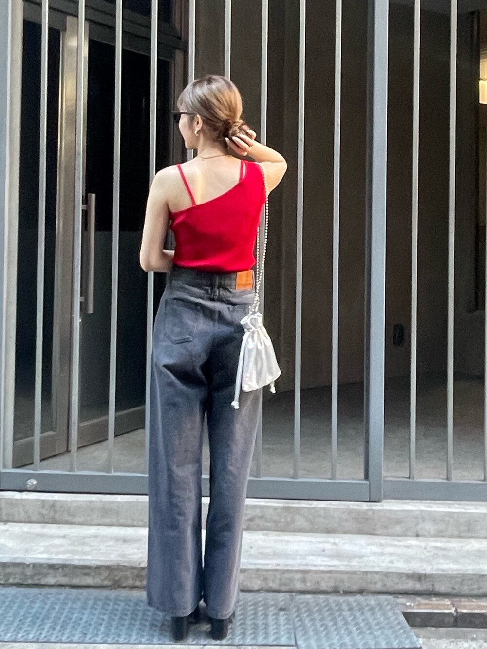 レッド系のニット/セーター、ブラック系のサンダル、ブラック系のデニムパンツを着用したレディースの春コーディネートの3枚目の写真