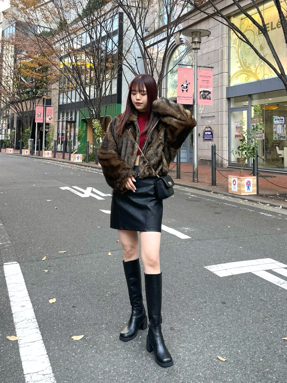 ブラック系のブーツ、ブラック系のスカート、レッド系のニット/セーターを着用したレディースの冬コーディネートの2枚目の写真