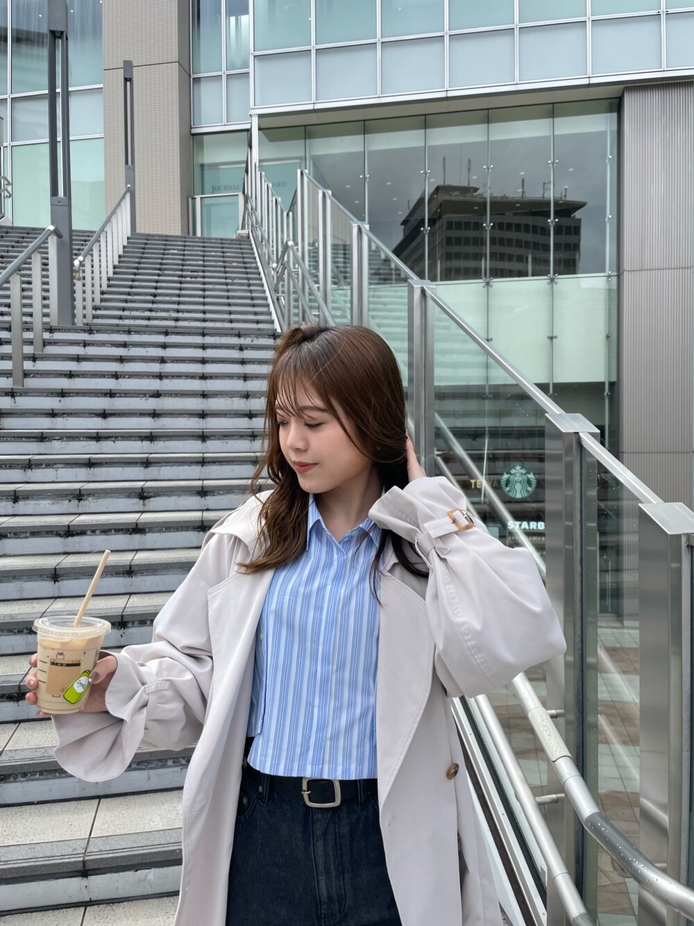 ホワイト系のトレンチコート、ブラック系のサンダル、ブラック系のデニムパンツを着用したレディースの春コーディネートの5枚目の写真