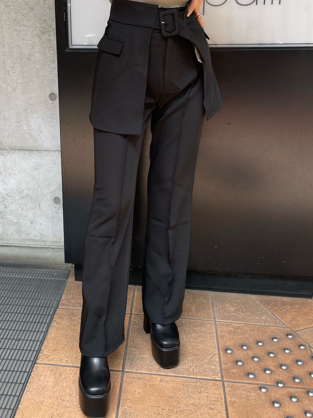 ブラック系のスラックス、ホワイト系のニット/セーター、ブラック系のブーツを着用したレディースの夏コーディネートの6枚目の写真