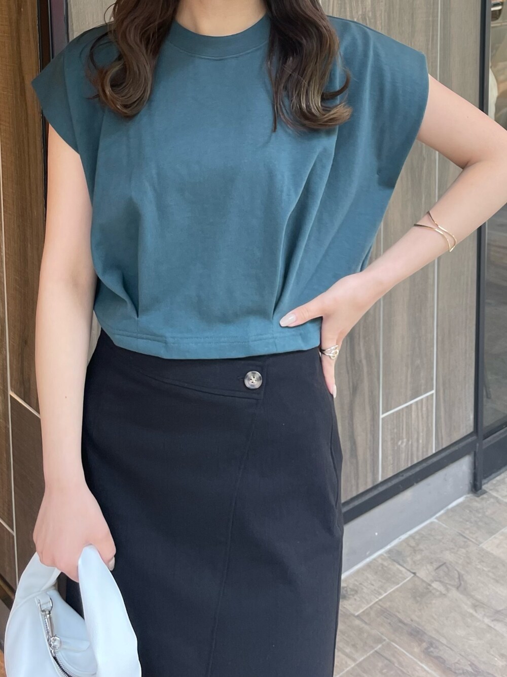 グリーン系のTシャツ/カットソー、ブラック系のスカート、ホワイト系のハンドバッグを着用したレディースの春コーディネートの4枚目の写真