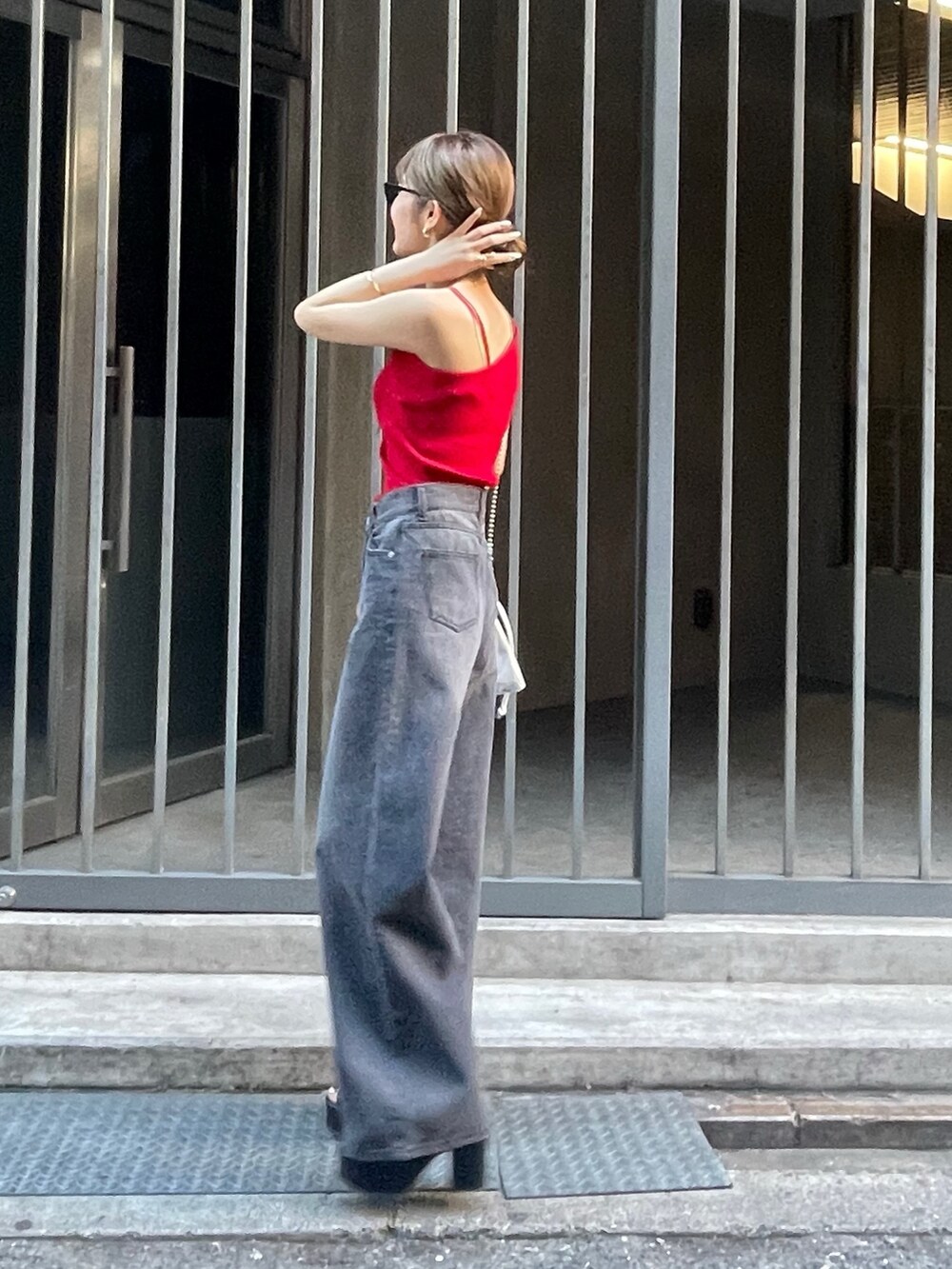 レッド系のニット/セーター、ブラック系のサンダル、ブラック系のデニムパンツを着用したレディースの春コーディネートの2枚目の写真