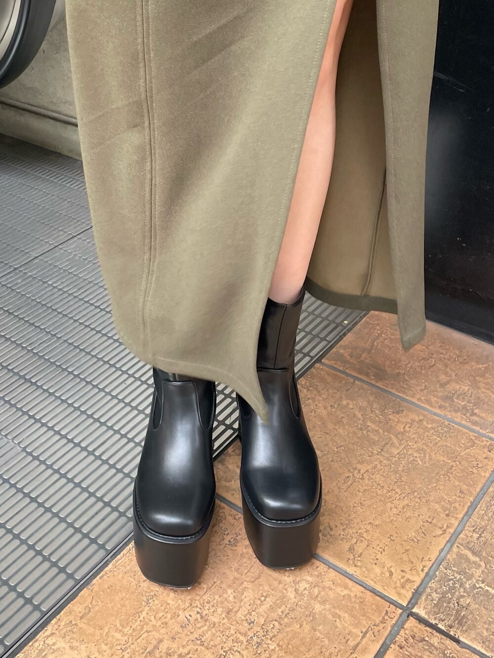 ブラック系のブーツ、グリーン系のスカート、ブラック系のニット/セーターを着用したレディースの冬コーディネートの8枚目の写真