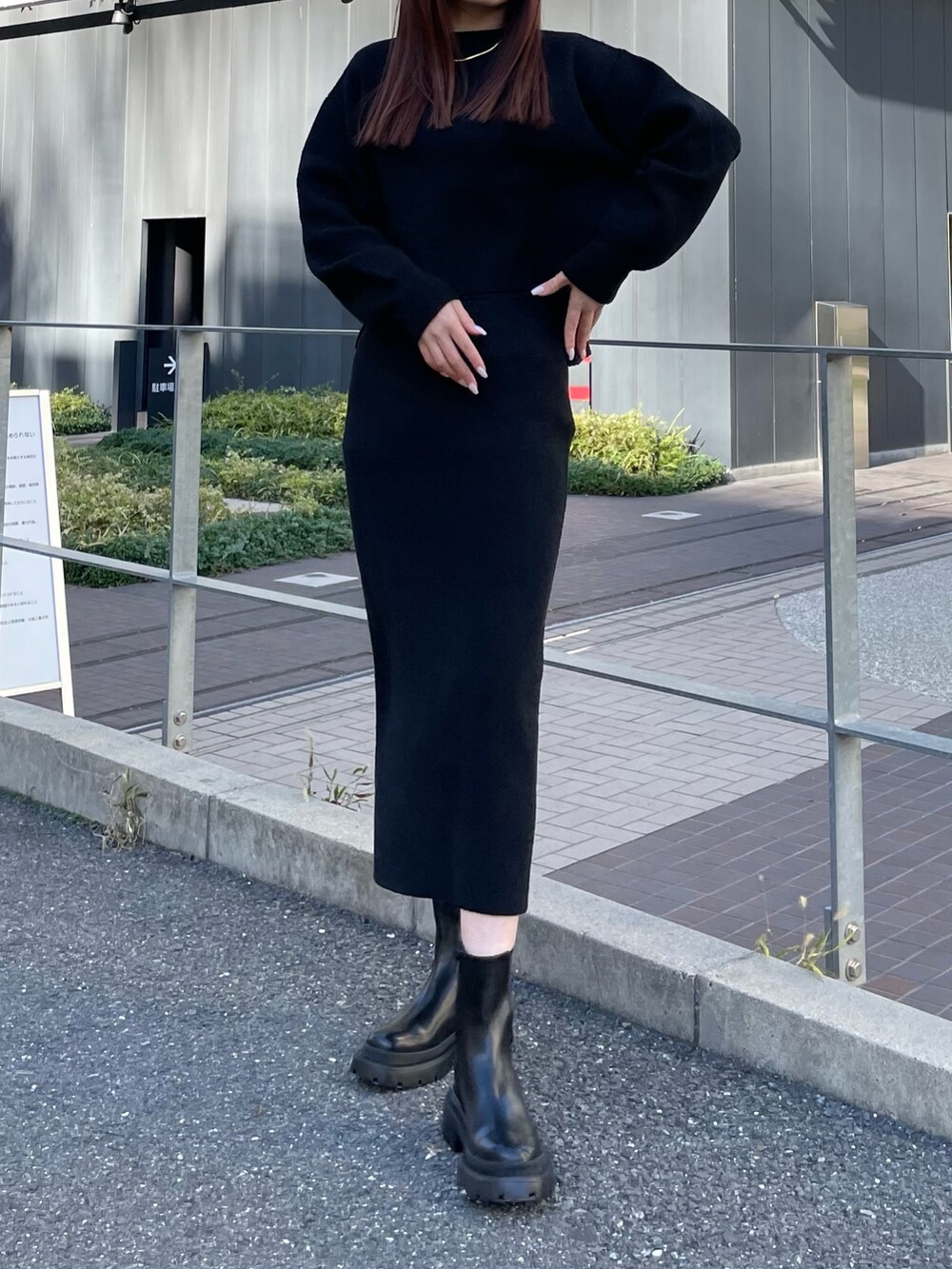 ブラック系のニット/セーター、ブラック系のスカート、ブラック系のブーツを着用したレディースの冬コーディネートの2枚目の写真