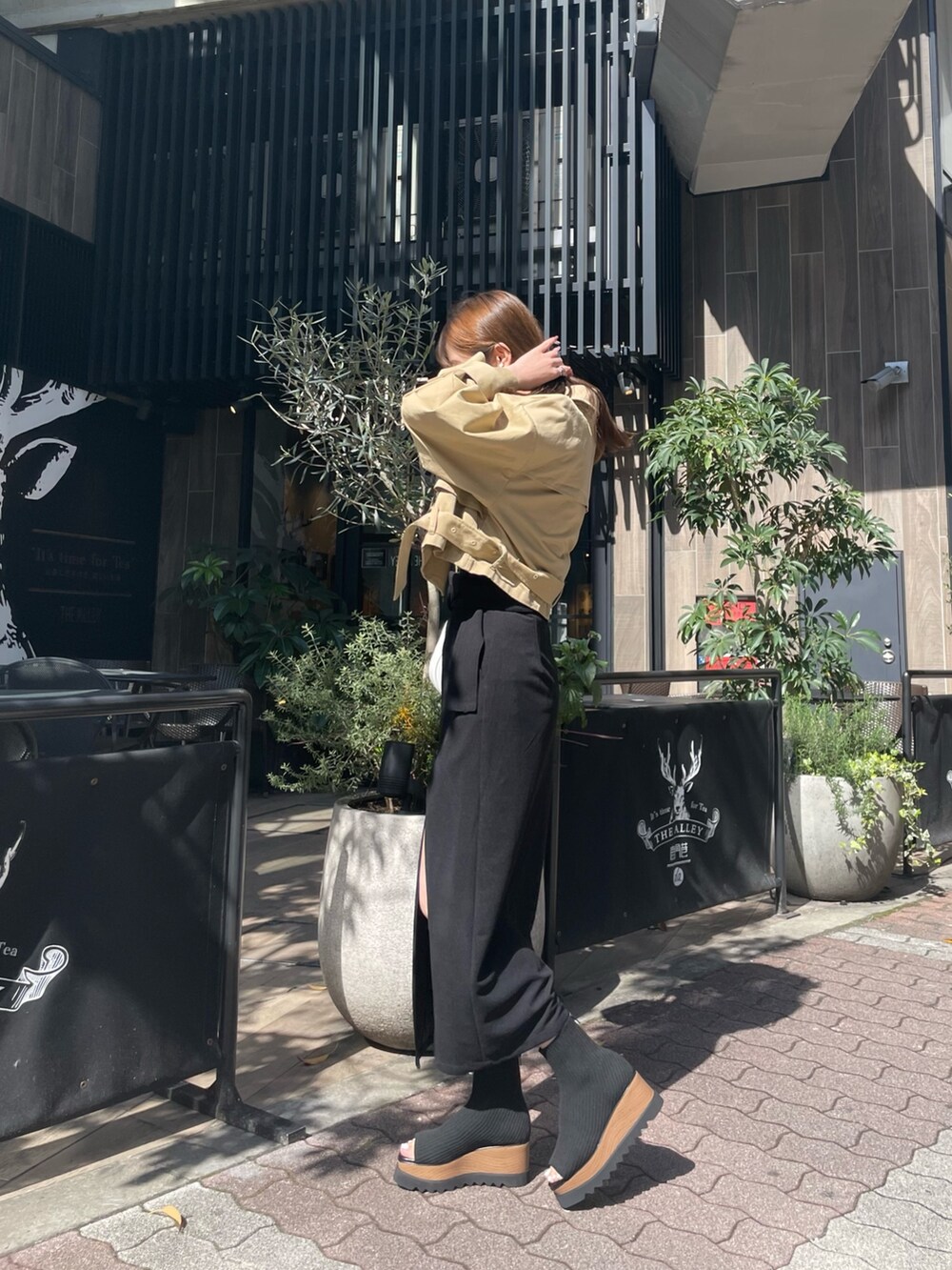 ホワイト系のハンドバッグ、ブラック系のブーツ、ブラック系のスカートを着用したレディースの春コーディネートの2枚目の写真