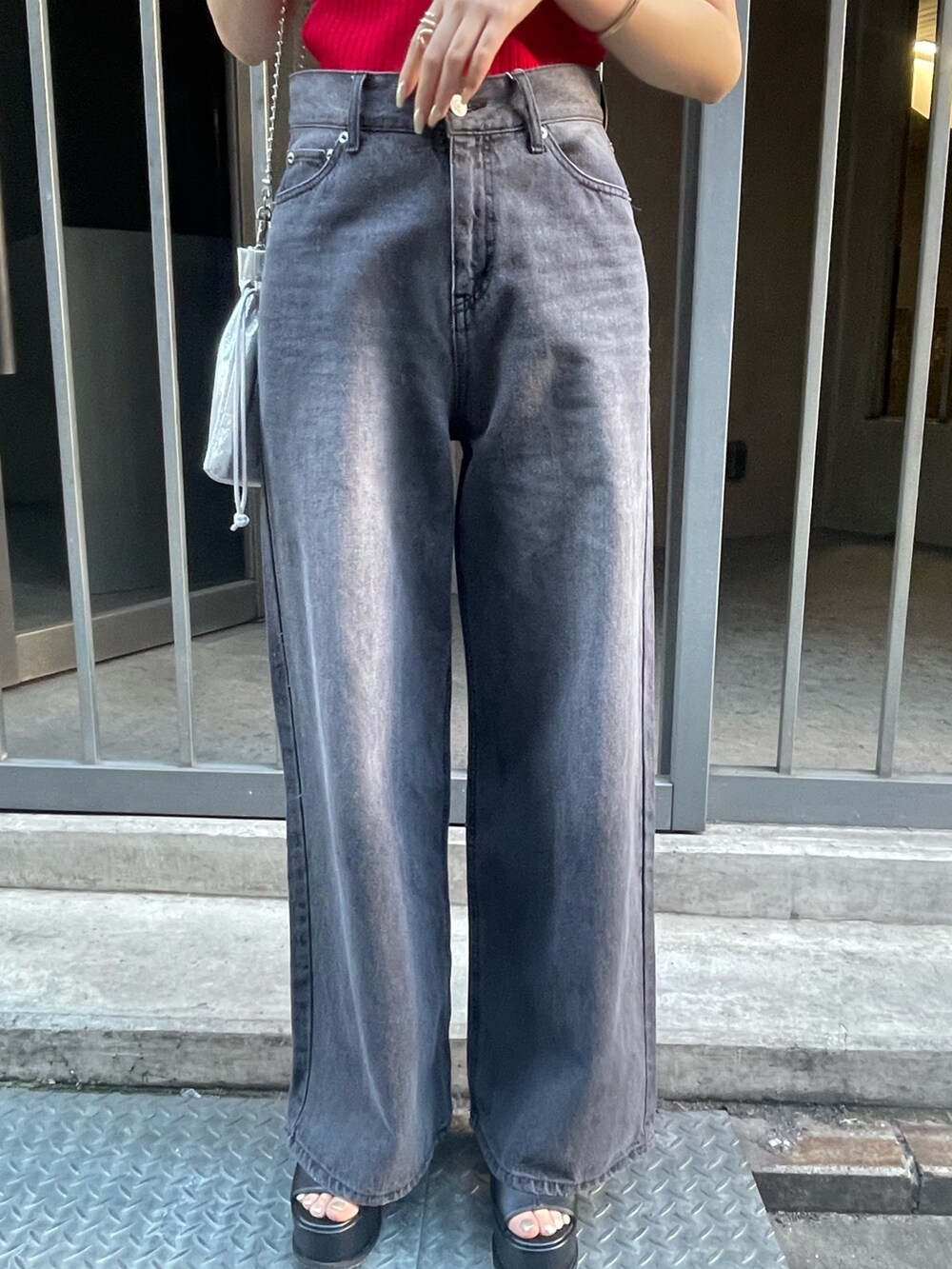 レッド系のニット/セーター、ブラック系のサンダル、ブラック系のデニムパンツを着用したレディースの春コーディネートの5枚目の写真