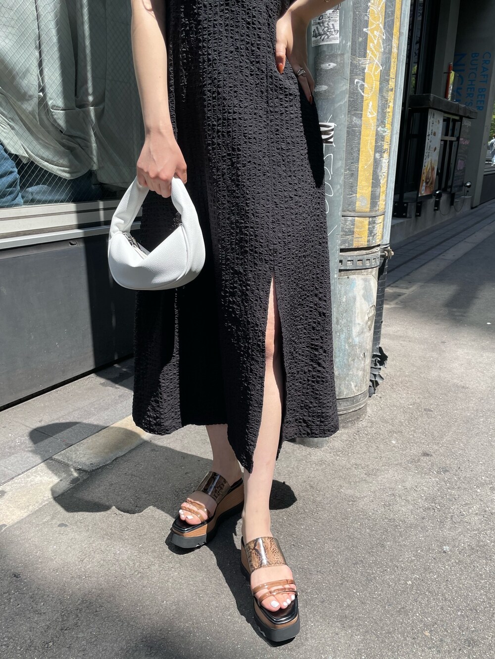 ホワイト系のハンドバッグ、ブラック系のサンダル、グリーン系のタンクトップを着用したレディースの春コーディネートの6枚目の写真