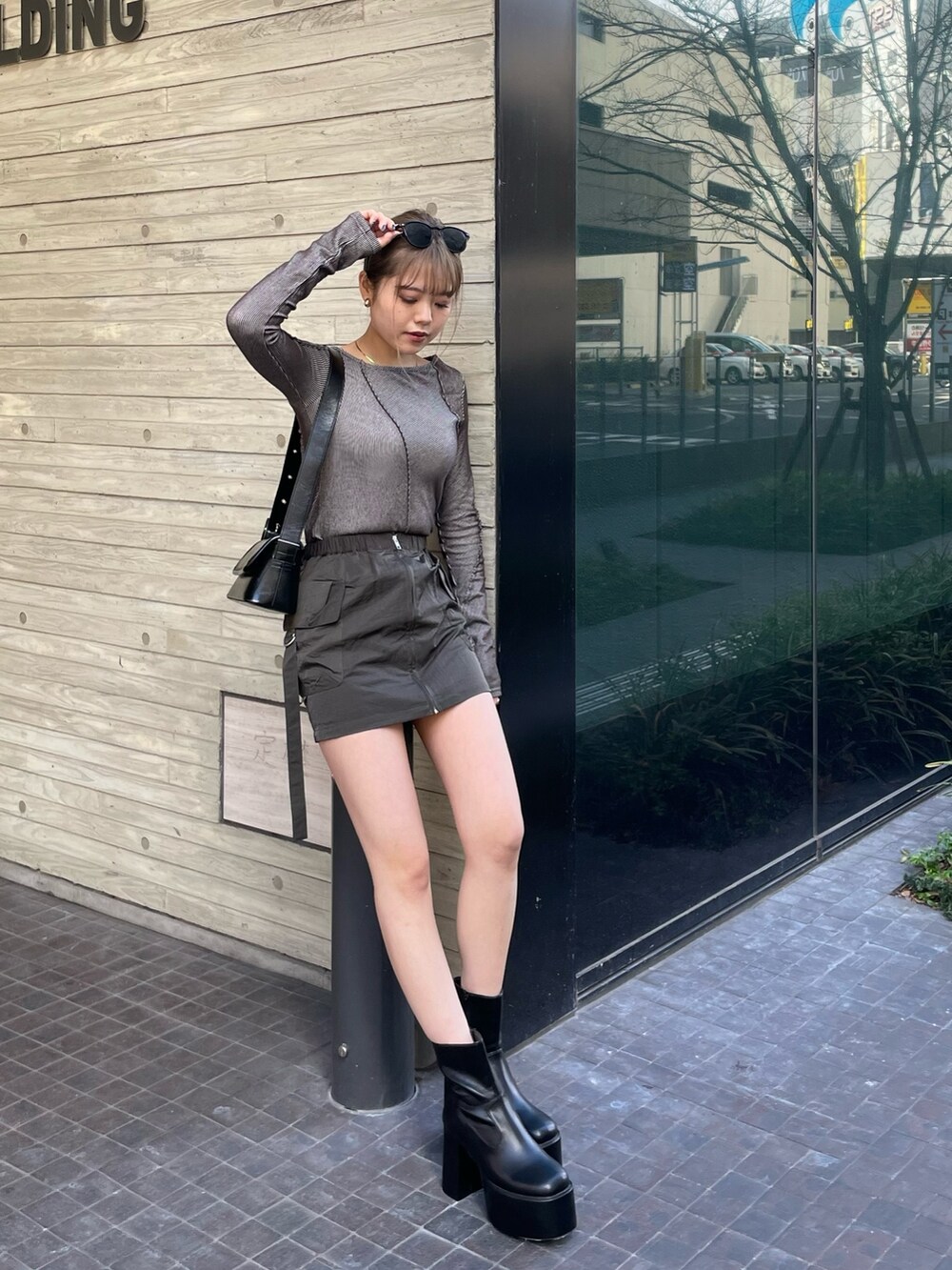 ブラック系のショルダーバッグ、グレー系のTシャツ/カットソー、ベージュ系のスカートを着用したレディースの冬コーディネートの2枚目の写真