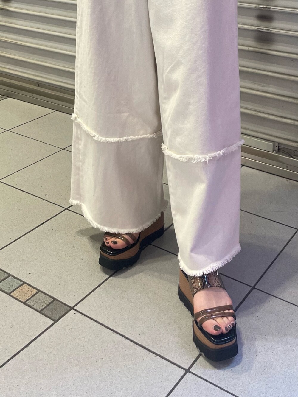 ブラック系のニット/セーター、ホワイト系のデニムパンツ、ブラック系のサンダルを着用したレディースの春コーディネートの7枚目の写真