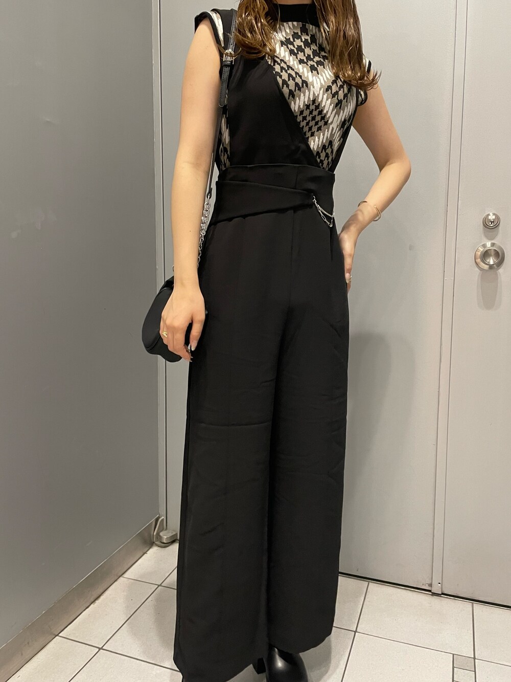 ブラウン系のニット/セーター、ブラック系のスラックス、ブラック系のハンドバッグを着用したレディースの夏コーディネートの5枚目の写真