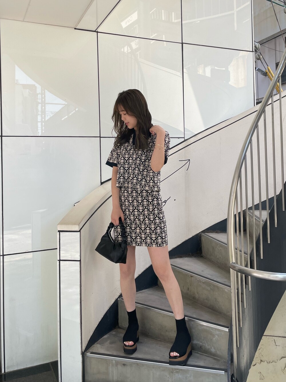 ブラック系のポロシャツ、ブラック系のスカート、ブラック系のブーツを着用したレディースの春コーディネートの2枚目の写真