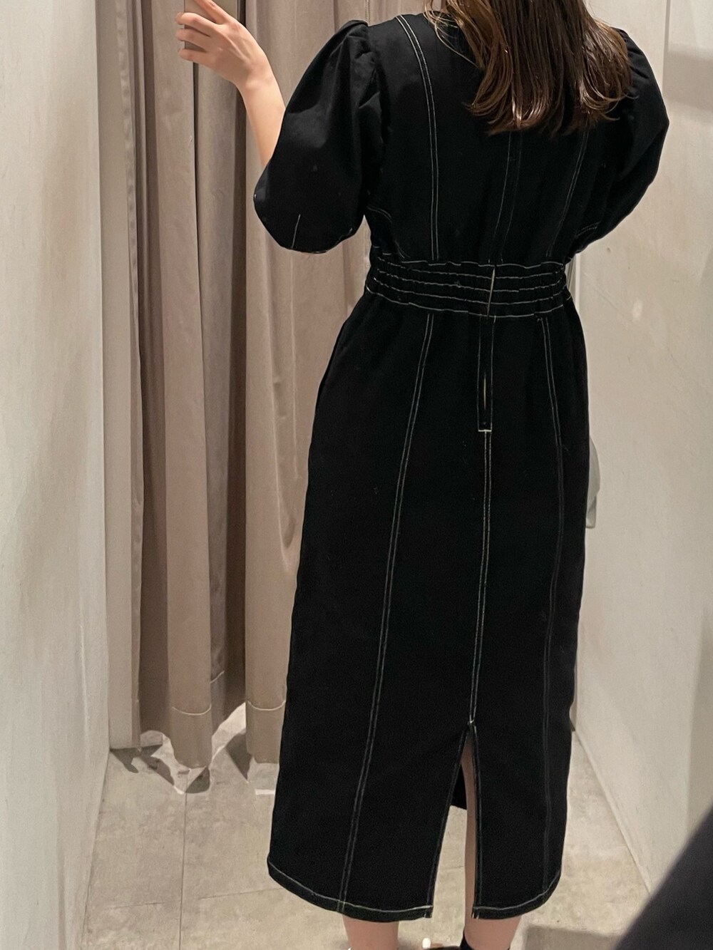 ブラック系のブーツ、ブラック系のワンピース、シルバー系のハンドバッグを着用したレディースの春コーディネートの3枚目の写真