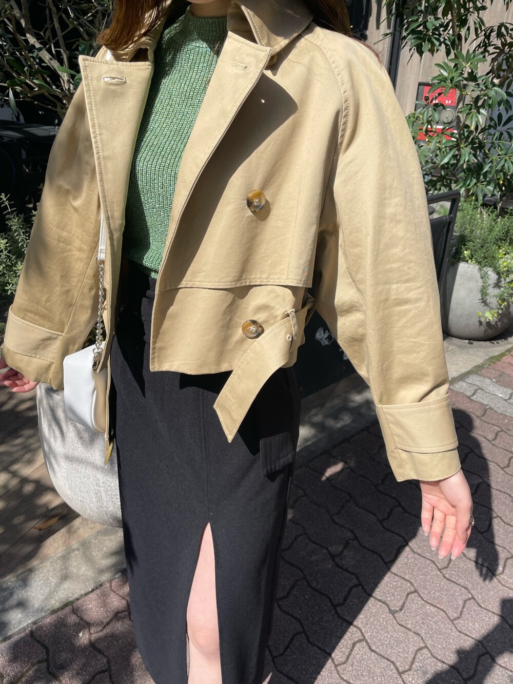 ホワイト系のハンドバッグ、ブラック系のブーツ、ブラック系のスカートを着用したレディースの春コーディネートの5枚目の写真