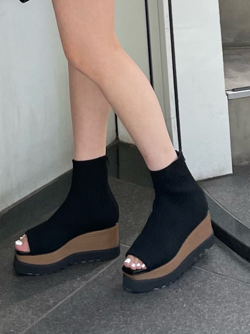 ブラック系のポロシャツ、ブラック系のスカート、ブラック系のブーツを着用したレディースの春コーディネートの8枚目の写真