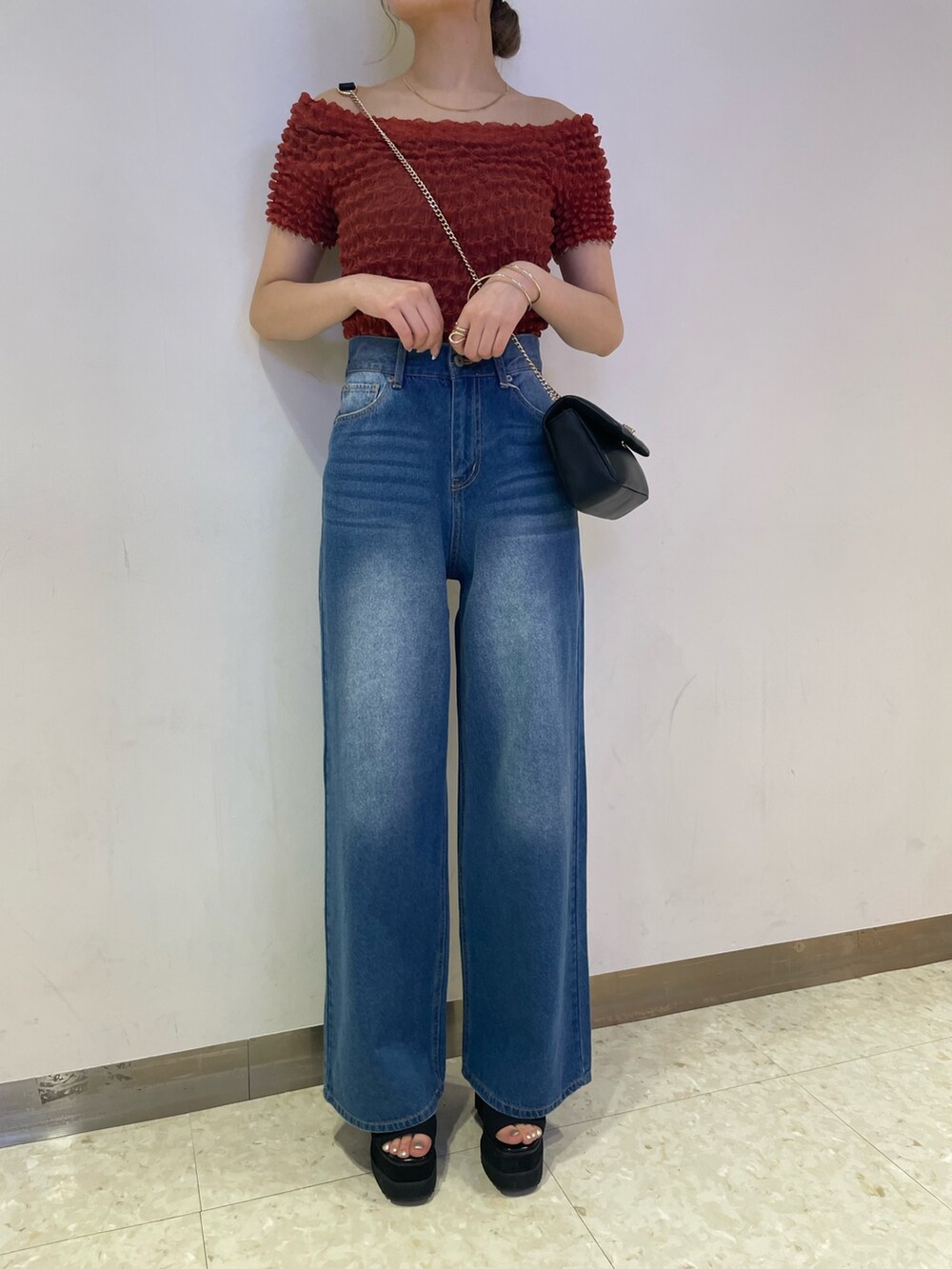 ブルー系のデニムパンツ、ブラック系のブーツ、レッド系のシャツ/ブラウスを着用したレディースの春コーディネートの6枚目の写真