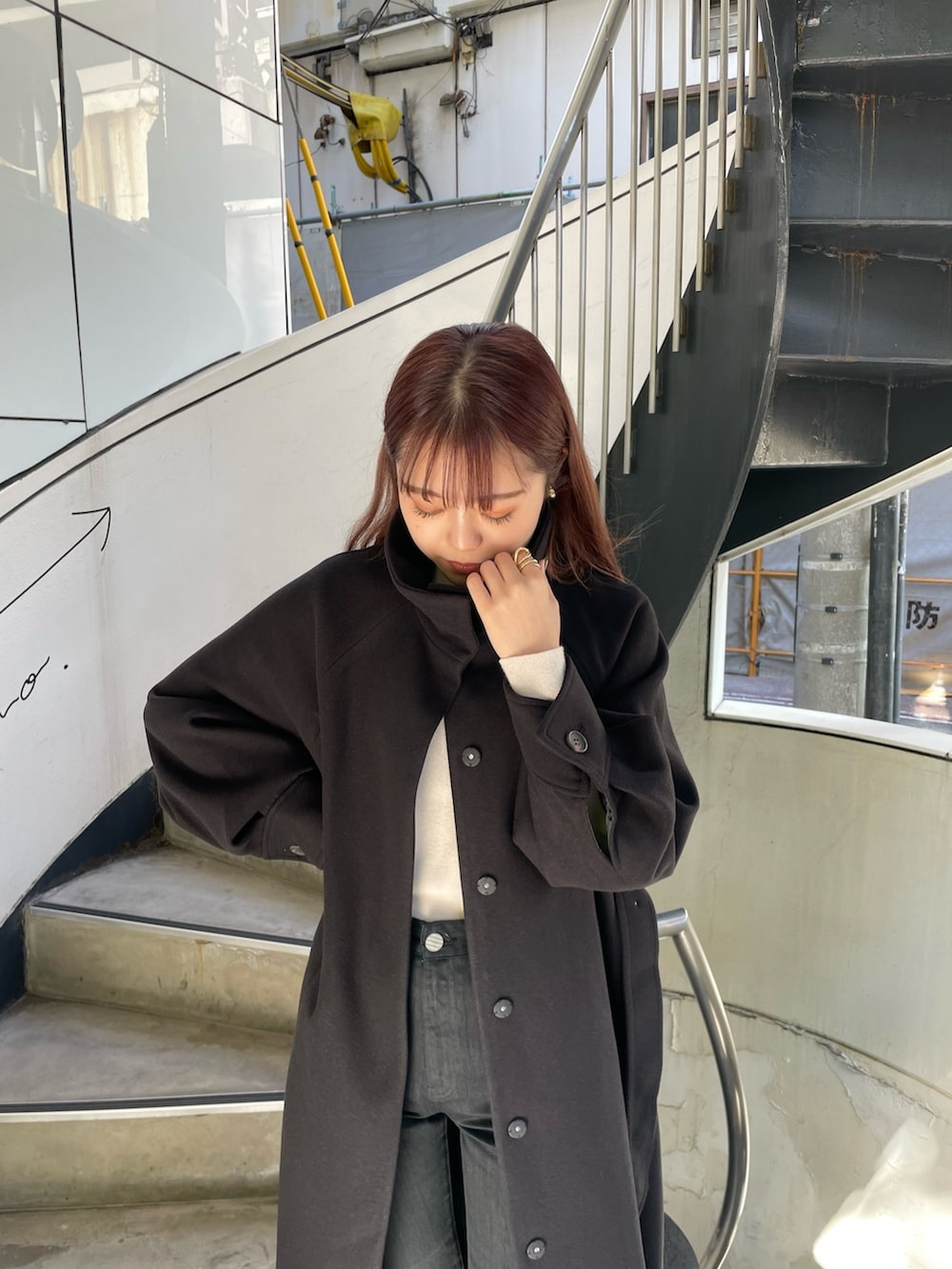 ブラック系のステンカラーコート、ホワイト系のニット/セーター、ブラック系のデニムパンツを着用したレディースの秋コーディネートの5枚目の写真