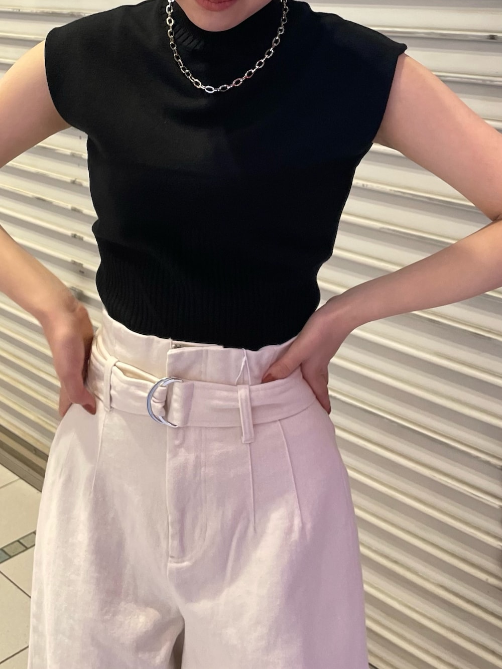 ブラック系のニット/セーター、ホワイト系のデニムパンツ、ブラック系のサンダルを着用したレディースの春コーディネートの5枚目の写真