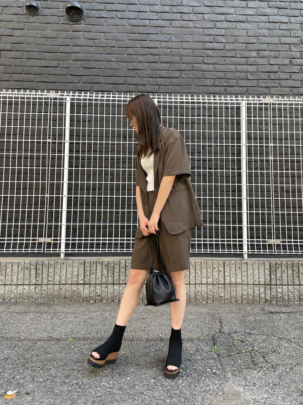 ブラウン系のテーラードジャケット、ホワイト系のタンクトップ、ブラウン系のスラックスを着用したレディースの春コーディネートの2枚目の写真