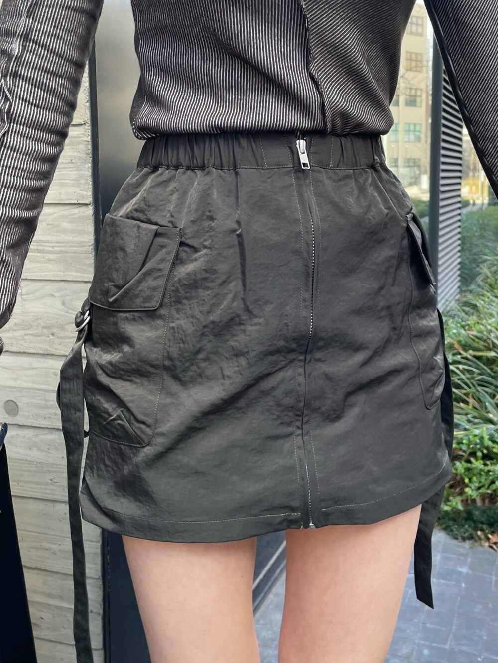 ブラック系のショルダーバッグ、グレー系のTシャツ/カットソー、ベージュ系のスカートを着用したレディースの冬コーディネートの6枚目の写真