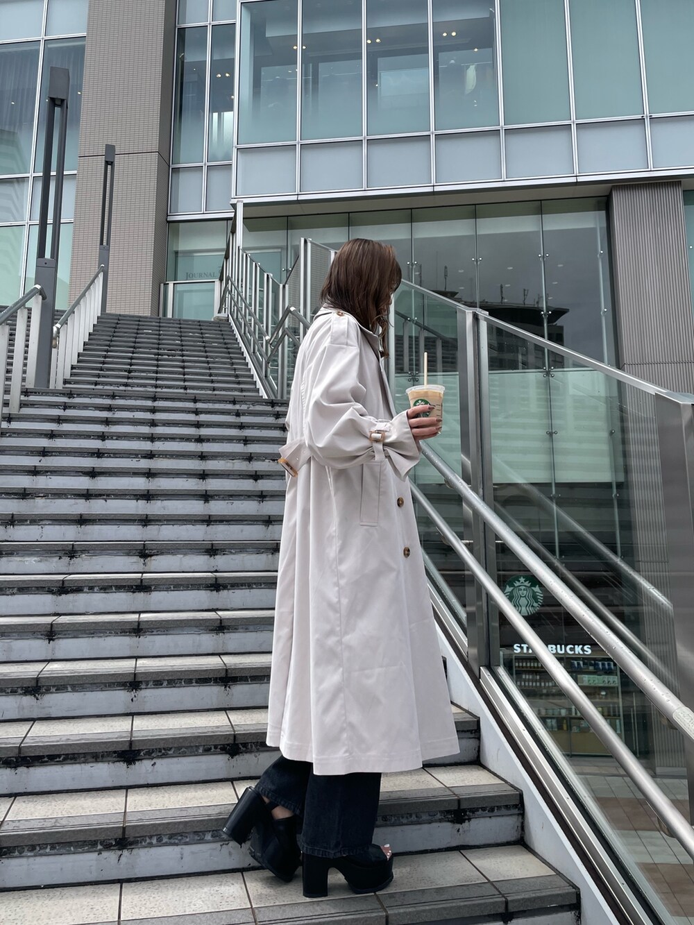 ホワイト系のトレンチコート、ブラック系のサンダル、ブラック系のデニムパンツを着用したレディースの春コーディネートの3枚目の写真