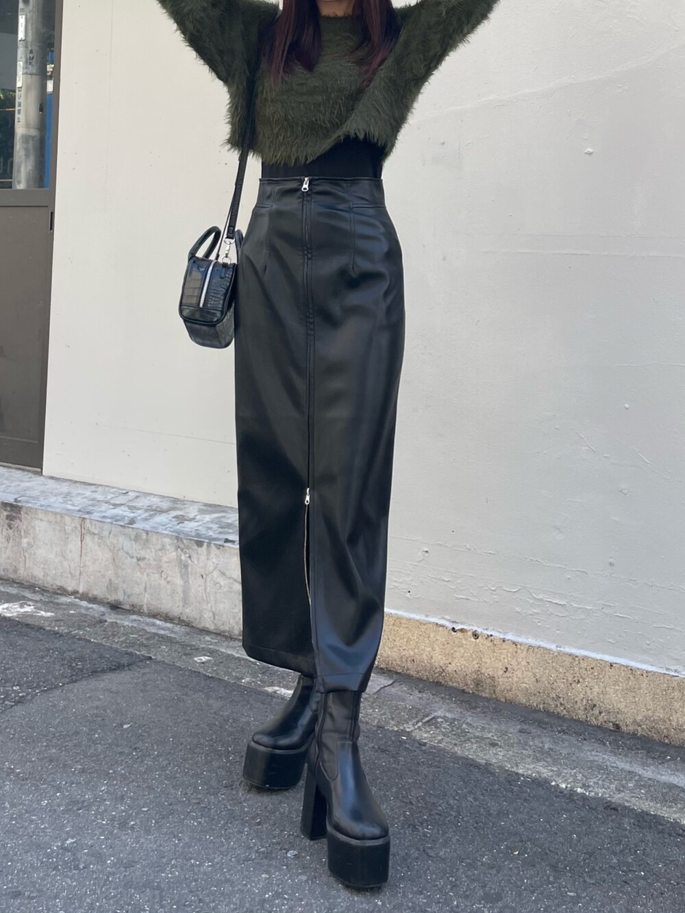 グリーン系のニット/セーター、ブラック系のボストンバッグ、ブラック系のスカートを着用したレディースの秋コーディネートの4枚目の写真