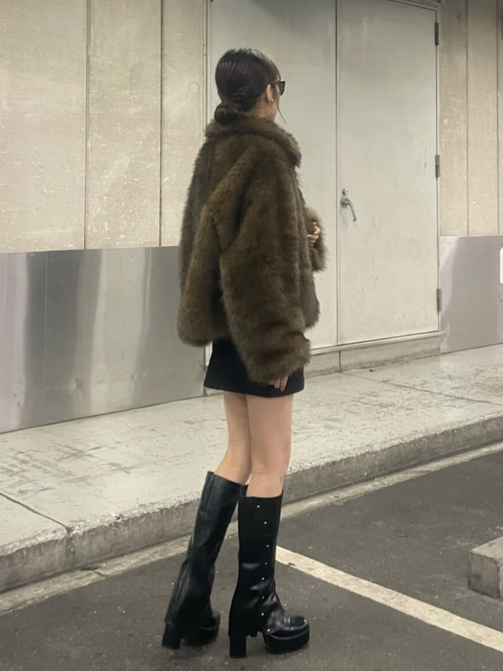 ブラウン系のブルゾン、ブラック系のスカート、ブラック系のブーツを着用したレディースの秋コーディネートの2枚目の写真