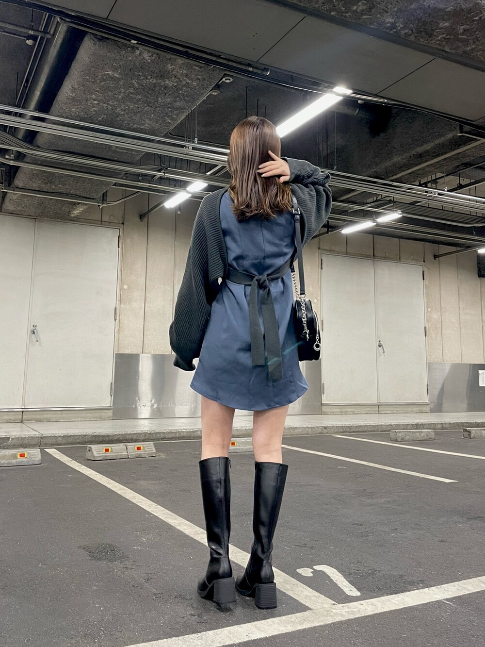グレー系のワンピース、ブラック系のショルダーバッグ、ブラック系のブーツを着用したレディースの冬コーディネートの3枚目の写真