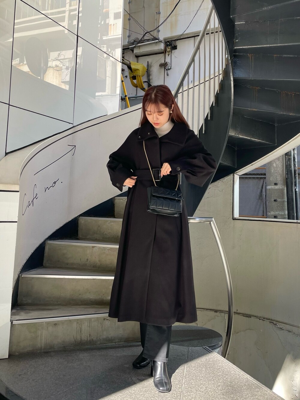 ブラック系のステンカラーコート、ホワイト系のニット/セーター、ブラック系のデニムパンツを着用したレディースの秋コーディネートの2枚目の写真